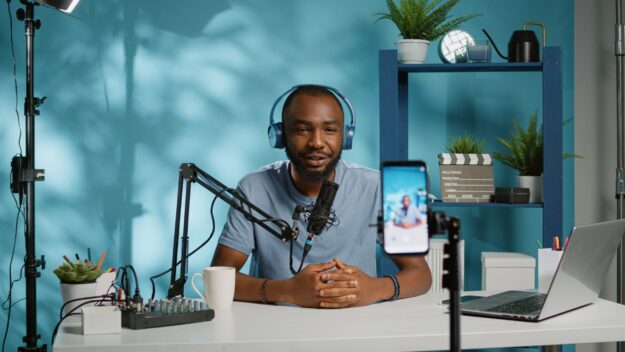 Blogger,Waving,At,Smartphone,Camera,For,Social,Media,Vlog.,Influencer Speaking Test Mittlere Reife Bayern: Praktisches Beispiel für Part 3 zum Thema 'Being Famous'